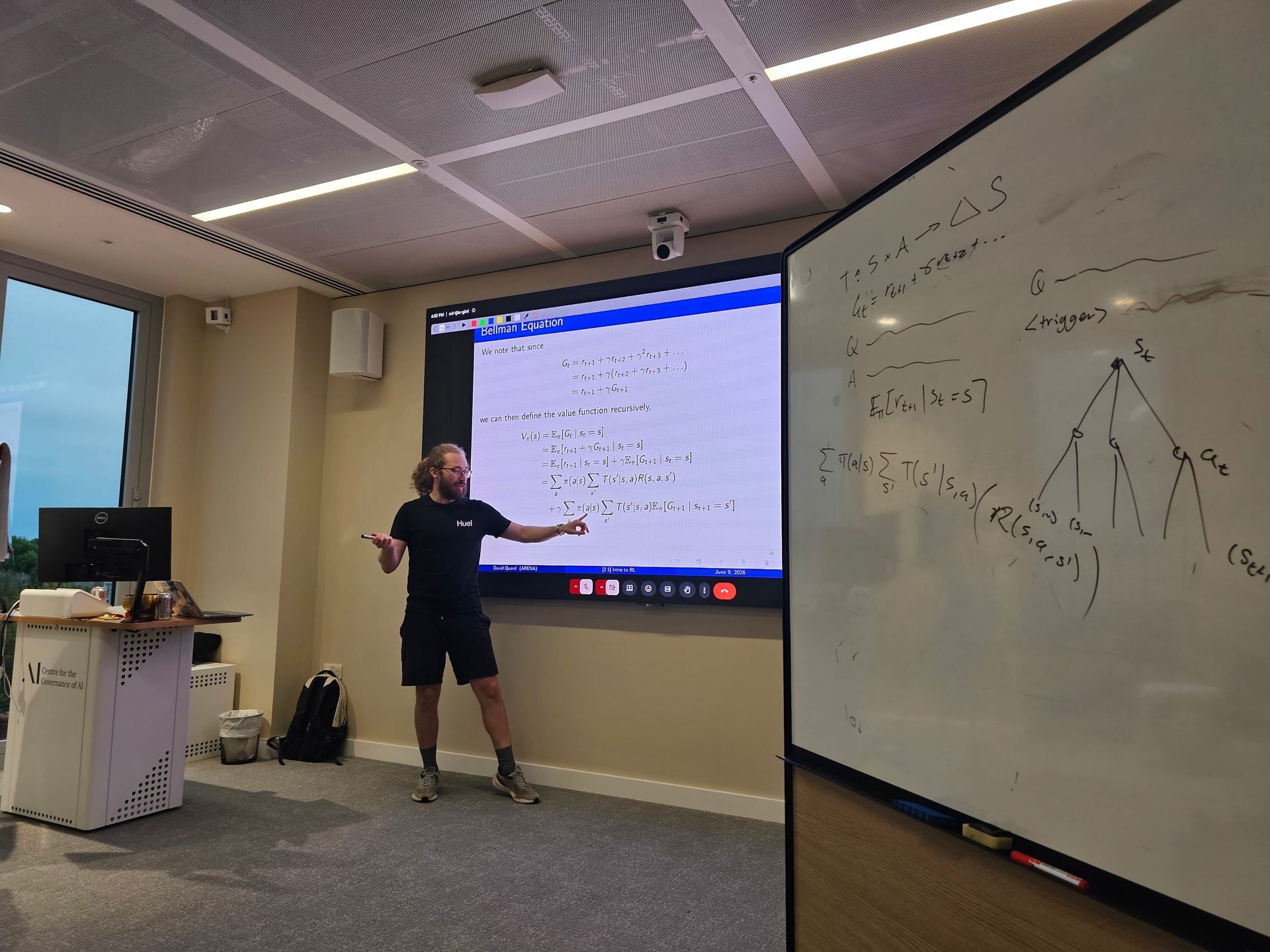 Oficina de GovAI donde se llevó acabo el AI Security Bootcamp (AISB) durante una sesión de reinforcement learning, con la ecuación de Bellman proyectada y notas en el pizarrón